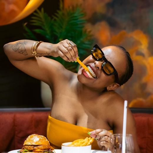 Someone eating chips and a burger in a brightly lit restaurant booth