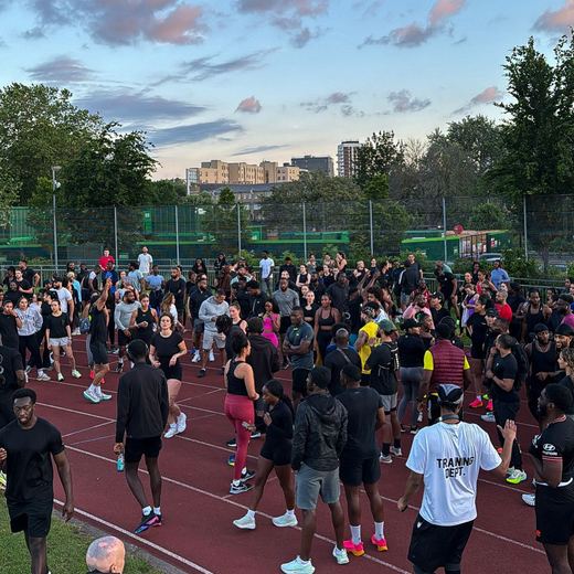 A large running group gathered on an athletics track at dusk